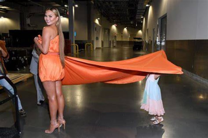 Chrissy Teigen’s Daughter Luna, 5, Hilariously Hides Under Her Gown At VAX Live Concert — Pics