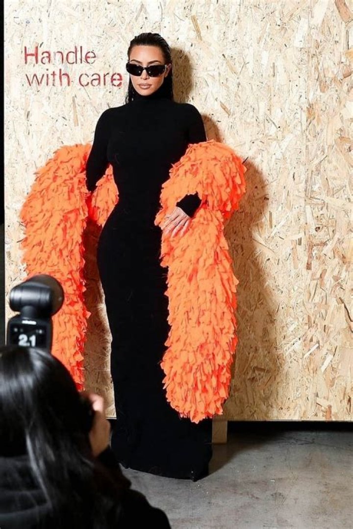 Kim Kardashian Jets Out Of Paris In Orange Feather Boa & Black Dress After Balenciaga Show